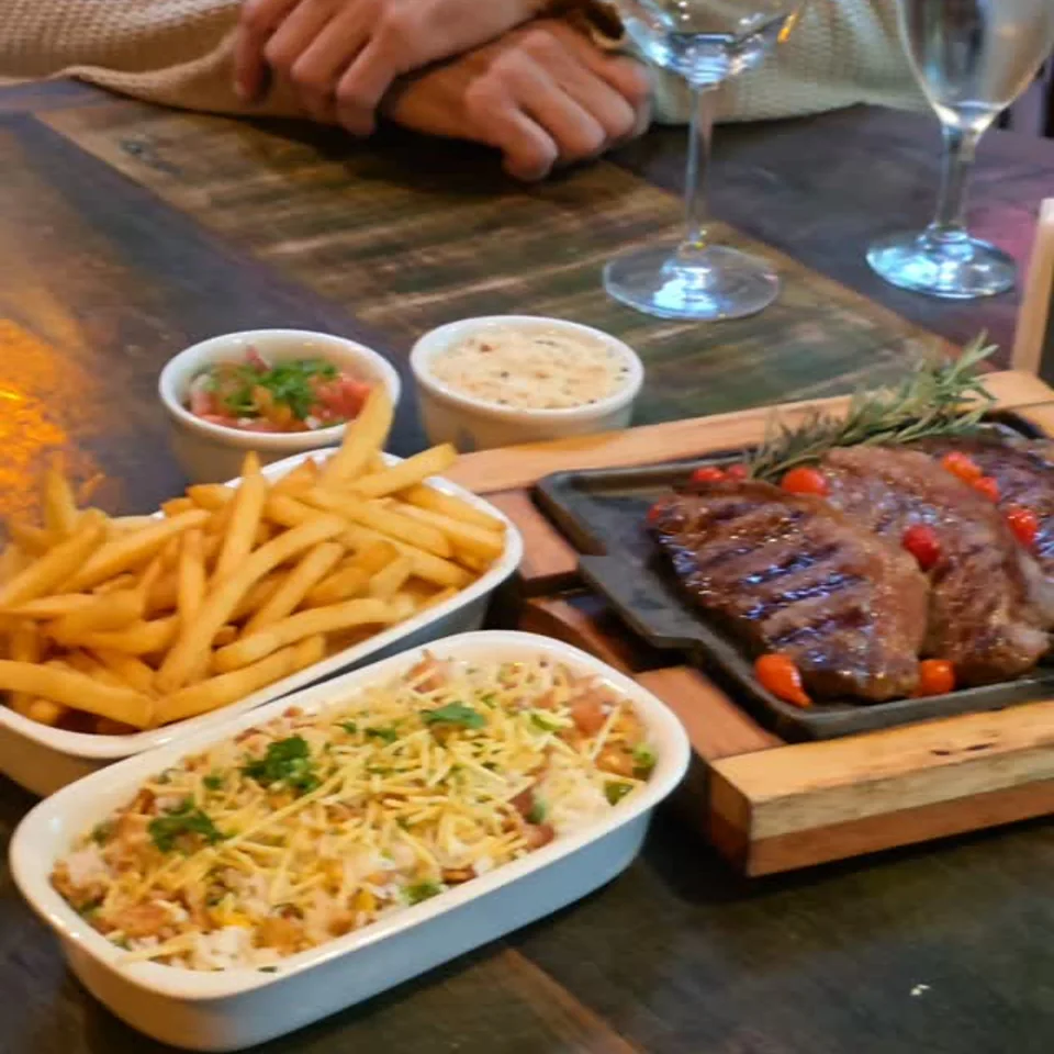 Picanha na chapa acompanhada de arroz e batatas fritas.